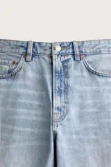 Jeans de denim de algodón en color azul con efecto desgastado, tiro medio y corte recto de ajuste holgado (loose fit). Cuenta con diseño clásico de cinco bolsillos y cierre frontal con cremallera y botón.