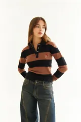 Top de manga larga con diseño de rayas horizontales en tonos negro y marrón, cuello polo con cierre de botones y bordado pequeño en el pecho.