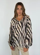 Blusa de manga larga con estampado animal print de cebra en tonos beige y negro, con cuello en V.