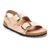 Sandalia Birkenstock modelo Milano con acabado brillante en color beige. Presenta dos correas ajustables con hebillas metálicas doradas y una correa trasera para mayor sujeción. Cuenta con plantilla ergonómica de corcho y suela de goma negra.