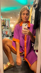 Conjunto de camisa de mangas cortas y short, color lila con detalles en naranja en cuello, mangas y ruedo.