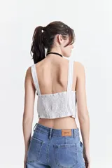 Top corto a rayas verticales azules y blancas, con escote recto y tirantes anchos.