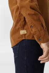 Camisa de pana color azul marino, con mangas largas, cuello clásico y dos bolsillos frontales con solapa y botón.