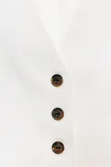 Chaleco negro con cuello en pico, sin mangas, bolsillos delanteros de vivo y cierre frontal con botones a contraste.