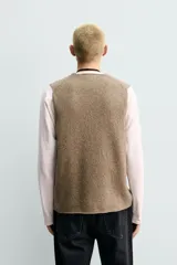 Chaleco regular fit de punto tejido en hilatura con mezcla de lana, color marrón con efecto melange. Cuenta con cuello en V y manga sisa, con acabados acanalados.
