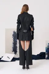 Mini falda negra con efecto cuero, de tiro medio y corte ajustado, que incorpora una estructura inferior tipo pantalón con aberturas laterales en los muslos.