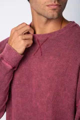 Buzo de corte oversize confeccionado en tela waffle de algodón con proceso de teñido acid wash. Presenta cuello redondo con detalle de costura en X y mangas largas con puños acanalados.