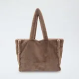 Bolso tipo tote confeccionado en tejido de pelo sintético suave, con diseño minimalista y asas superiores fijas.
