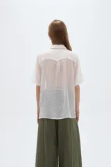 Blusa blanca de lyocell con cuello solapa, mangas cortas y cierre frontal mediante cordones para anudar.