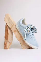 Zapatillas bajas color marrón con cordones y charms dorados.