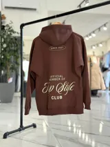 Canguro oversize de color marrón, con capucha y estampa en la espalda con el texto "Official Member of Top Style Club".