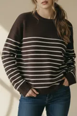 Sweater marrón con rayas horizontales blancas, de corte holgado y manga larga. Tejido suave y liviano de viscosa, poliéster y poliamida.