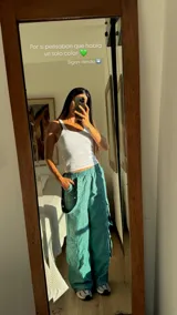 Pantalón estilo cargo parachute color blanco, de corte holgado, con cintura elástica y bolsillos laterales amplios con detalles de tiras y botones a presión.