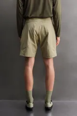 Pantalón corto de estilo técnico, color beige, con ajuste regular. Cuenta con cintura ajustable mediante cinturón de doble hebilla, cierre frontal con cremallera y botón a presión, bolsillos laterales y bolsillos con cremallera oculta.