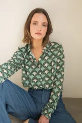 Camisa de manga larga con cuello camisero y cierre frontal de botones, confeccionada en tela estampada con un patrón geométrico de abanicos en tonos verdes y beige.