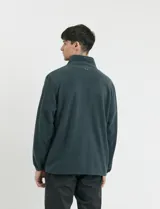 Campera de micropolar color verde oscuro, con cuello alto, cierre frontal completo, bolsillos laterales y un bolsillo con cierre en el pecho.