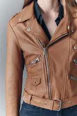 Campera estilo biker confeccionada en cuero ovino, con solapas amplias, charreteras en los hombros y cinturón ajustable en la cintura. Presenta cierres metálicos en el frente y bolsillos laterales, con forro interior de poliéster.