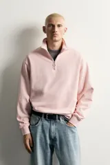 Sudadera de corte regular fit en color rosado, con cuello subido y cierre frontal de cremallera. Presenta manga larga y acabados en rib en puños y ruedo.