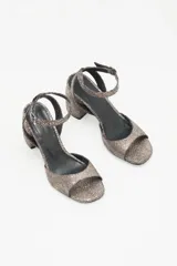 Sandalias de cuero vacuno color peltre con textura craquelada, tira delantera y tobillera con hebilla metálica, forro de cuero caprino y suela de cuero reconstituido con taco geométrico.