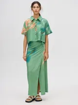 Falda larga tipo pareo con diseño envolvente, confeccionada en viscosa con estampado abstracto en tonos verdes, naranjas y azules. Presenta tiras ajustables en la cintura y una abertura frontal.