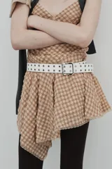 Vestido corto con escote en V y tirantes finos ajustables, confeccionado en tejido a cuadros beige y rojo. La falda es asimétrica y presenta un bajo con detalle de encaje.