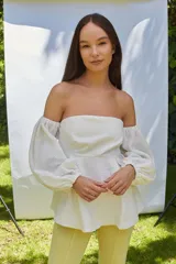 Blusa blanca con escote strapless y mangas largas abullonadas con puños elásticos.