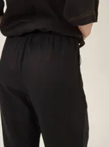 Pantalón de lino color tostado, de corte amplio y fluido con piernas acampanadas.