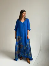 Vestido largo azul con cuello en V, mangas tres cuartos y gran estampado floral en la parte inferior.