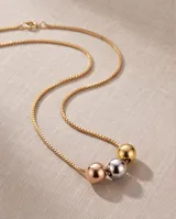 Collar de cadena veneciana de acero con baño dorado, decorado con tres dijes centrales en forma de esfera en tonos oro, plata y oro rosado.