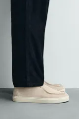 Zapato casual de hombre, color beige claro, con capellada de serraje (gamuza) y cordones finos. Presenta un detalle de bordón en el empeine y suela gruesa de goma a contraste en color crema.