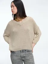 Sweater de punto con brillo, de corte relajado y escote en V. Presenta hombros caídos y mangas largas con puños acanalados.