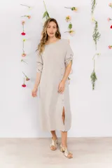 Vestido midi de lino color beige, con corte recto, cuello redondo y mangas 3/4 con botón. Presenta una hilera de botones decorativos en el frente y un tajo lateral.