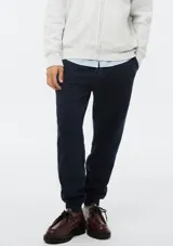 Pantalón tipo babucha de color azul oscuro, confeccionado con interior de felpa. Presenta cintura elástica con cordón de ajuste y puños acanalados en los tobillos.