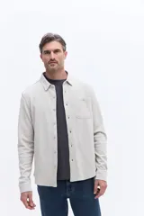 Camisa de manga larga en tejido de algodón con textura, cuello clásico, cierre frontal con botones y un bolsillo en el pecho.