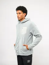 Campera con capucha y cierre frontal completo, confeccionada en tejido texturizado gris claro. Presenta un bolsillo frontal en el pecho de material contrastante con logo de la marca y bolsillos laterales.