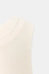 Top color beige con cuello redondo, manga sisa y bajo asimétrico. Confeccionado en hilatura de lyocell con efecto doble.