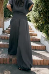 Pantalón baggy de tiro medio color rosado, con cintura elástica fruncida tipo nido de abeja y bajos ajustables con cordones.