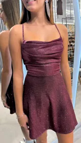 Vestido corto bordó con brillos, escote drapeado, tirantes finos y falda evasé.