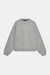 Sudadera gris de cuello redondo y manga larga, con puños y dobladillo acanalados.