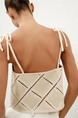 Top de escote recto color beige con tirantes finos ajustables con lazadas. Presenta un diseño con apliques de tejido tipo crochet en patrón geométrico de rombos.