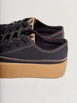 Championes de lona negra con plataforma y puntera de goma marrón, cordones negros y costuras en contraste.