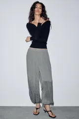 Pantalón de tiro medio con cintura elástica y bajo acabado en puño elástico. Presenta un diseño con tejido efecto arrugado y bolsillos laterales ocultos en costura.