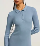 Vestido corto de corte evasé confeccionado en tejido de punto, con cuello polo, cierre frontal con botones y mangas largas.