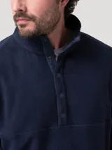 Buzo de polar color azul marino con cuello alto y cierre parcial de botones a presión en el frente. De manga larga y calce recto.