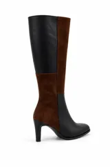 Bota alta bicolor con diseño de paneles en combinación de cuero negro y gamuza marrón. Cuenta con punta cuadrada suave, caña recta alta y taco fino.