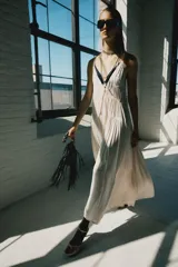 Vestido midi de satén color crudo, con escote en V, tirantes finos y detalle de lazada en el delantero.