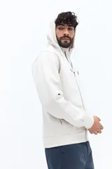 Campera de felpa color beige claro con capucha ajustable con cordones y bolsillos canguro. Presenta un pequeño texto estampado en la manga.