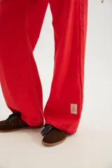 Pantalón de corte recto y tiro medio con costuras a la vista, bolsillos delanteros y traseros, y un detalle de pin de la marca en el ruedo.