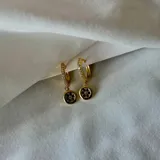 Aros dorados tipo argolla con strass y dije colgante circular con diseño de florcitas negras.