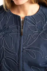 Campera tipo bomber color azul, con cierre frontal y diseño de bordado floral en toda la prenda. Presenta puños y ruedo con elástico, y un corte holgado.